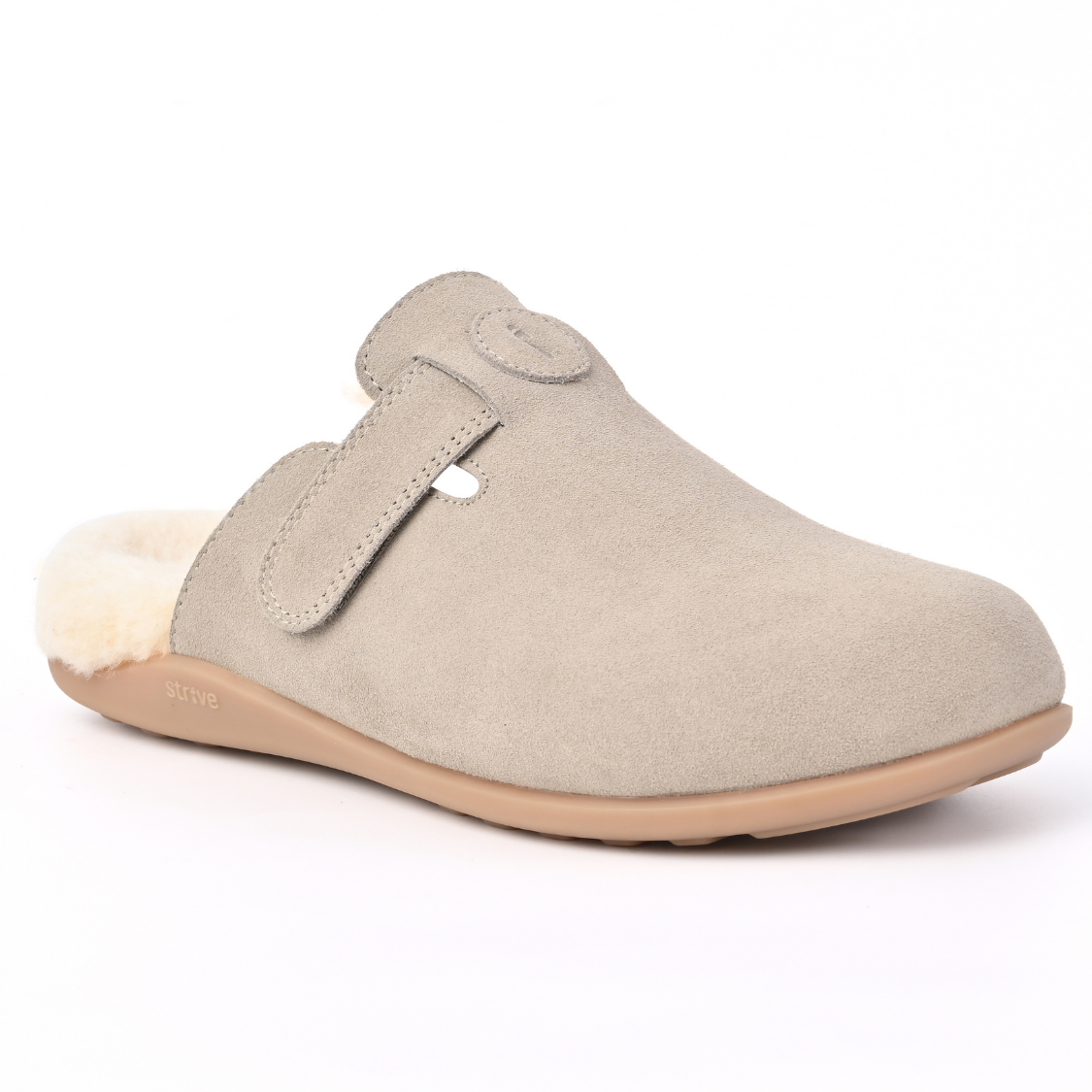 A light beige suede clog-style slipper with a soft cream shearling lining and a tan sole, shown from a side profile on a white background. Strive Footwear Oslo II Women’s Grey Slippers