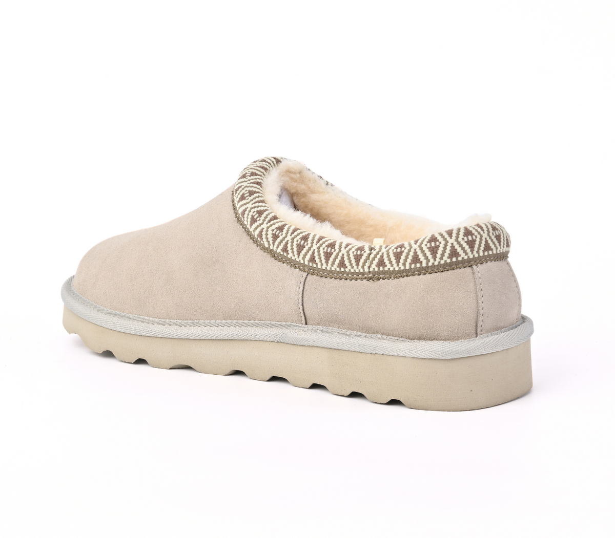 A single slip-on mule shoe in light beige suede with a cream sherpa lining and a geometric patterned trim around the collar, shown from a three-quarters angle on a white background.