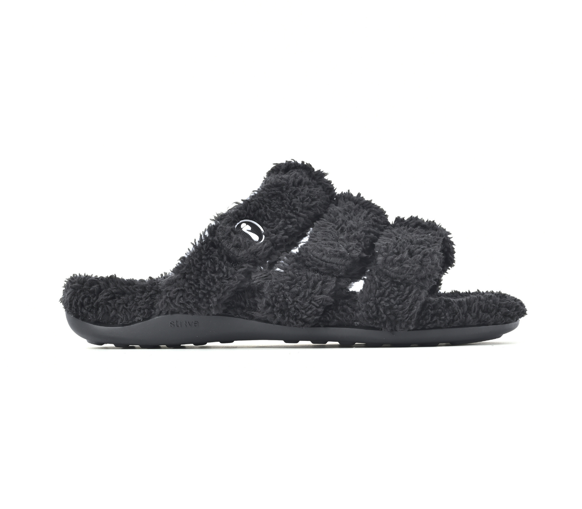 A pair of black fuzzy slide sandals with wide straps and a thick black sole, shown from a side profile on a white background.