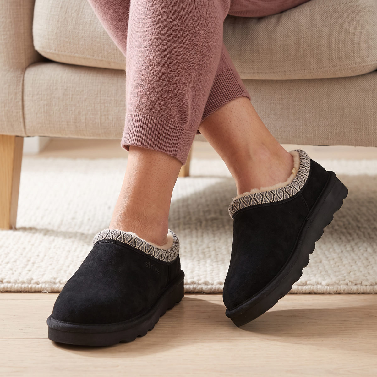 Woman wearing Black Strive Zella supportive slippers on a chair